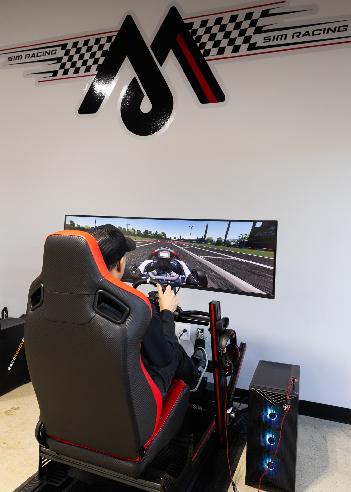 A driver in the seat of an MCK sim rig, on track in Assetto Corsa