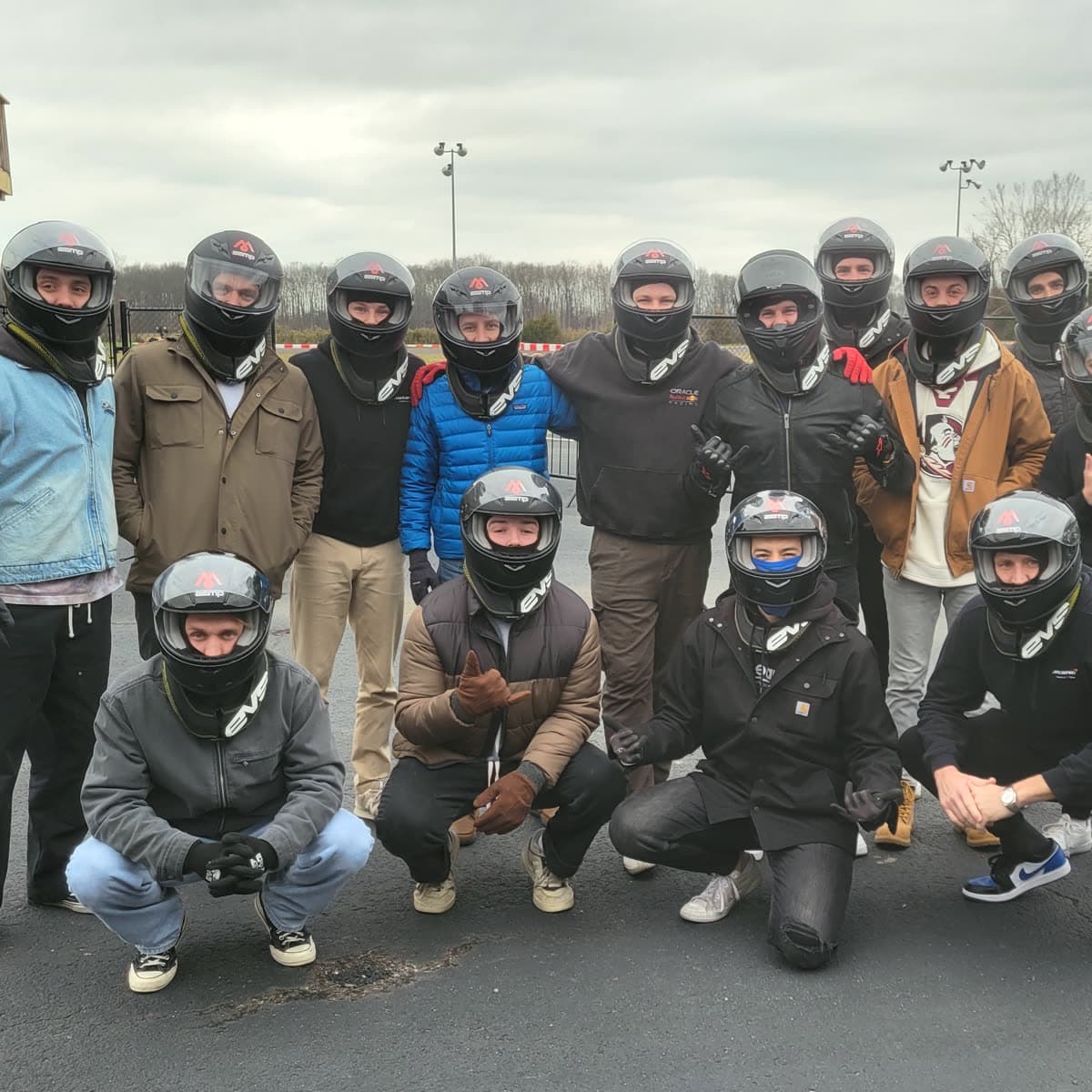 A group of drivers in helmets on the paddock after a session
